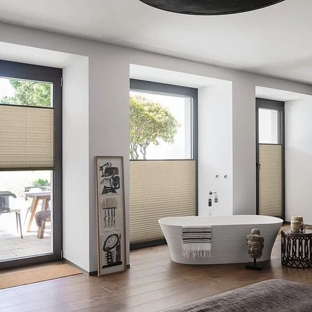 Badezimmer mit einer Badewanne und großen Fenstern, die viel Tageslicht hereinlassen.