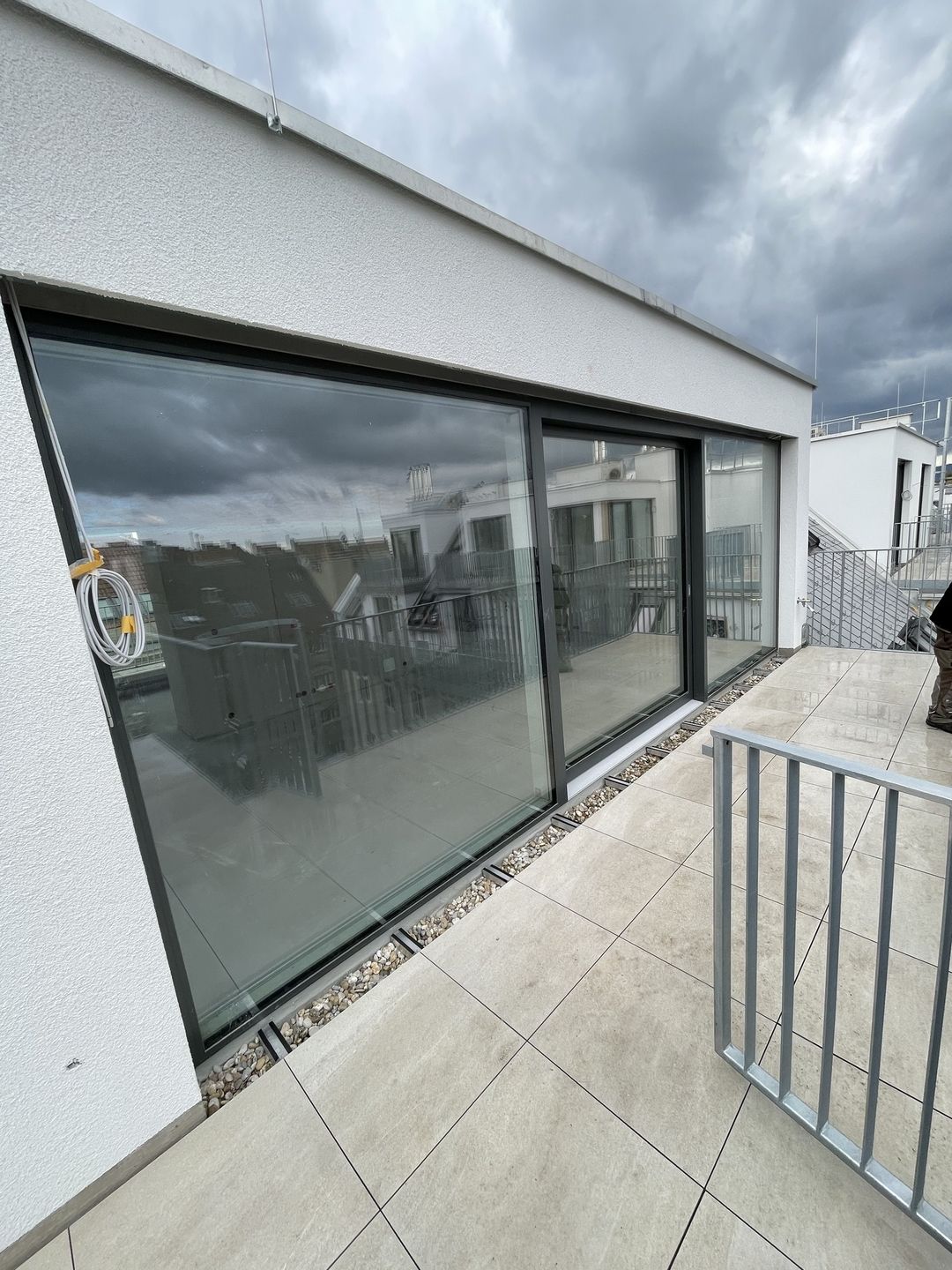 Eine Glastür mit Blick auf ein modernes Gebäude im Hintergrund, das die Umgebung reflektiert.